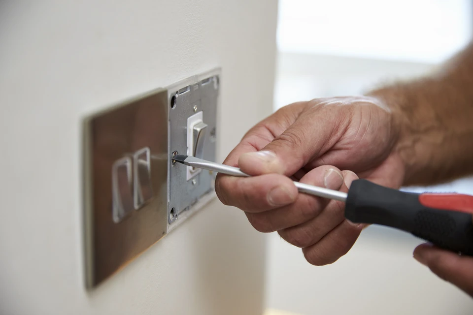 Architecte ou ingénieur en chemise à carreaux travaillant sur des plans techniques dans un bureau lumineux avec grande fenêtre donnant sur verdure